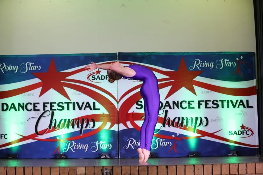 Thalia arching backwards from standing, arms reaching behind her