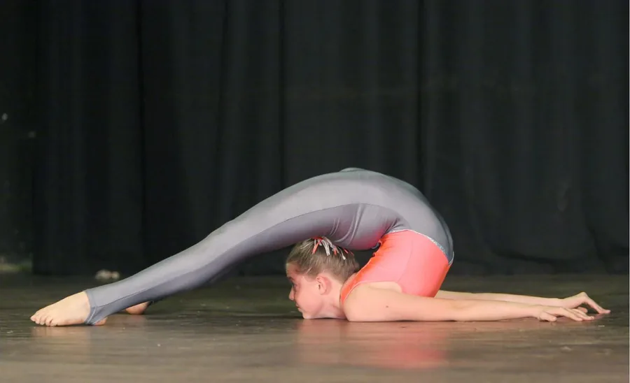 Thalia folded forward on the floor, legs arched over her head
